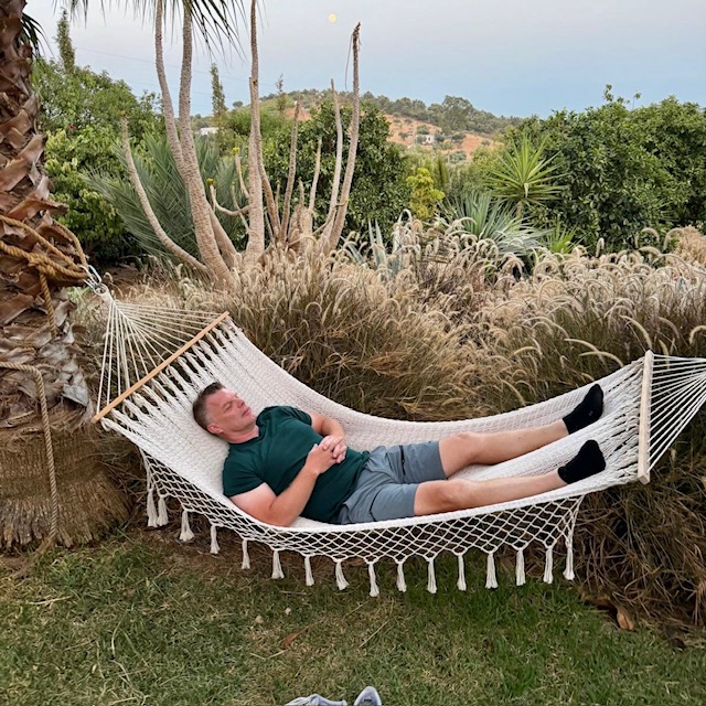 Ola resting in a hammock among palms and grasses in the garden
